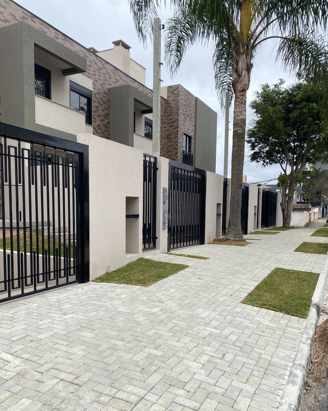 Calçada pública com paver e pequenos jardins frontais em casas